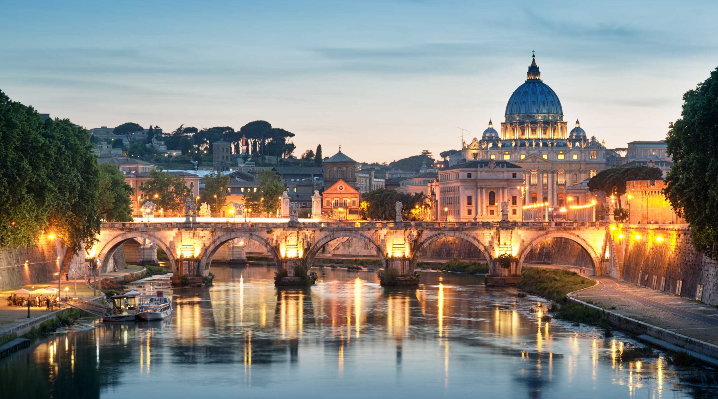 City skyline at night overlooking a river as the yellow lights, illuminate a bridge up the 